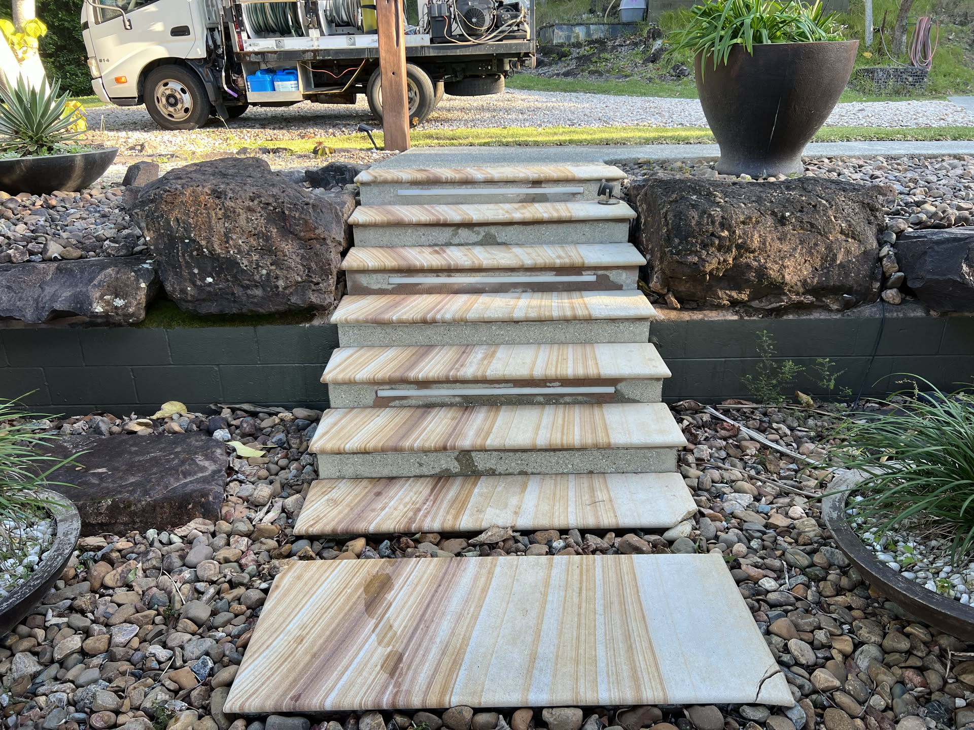 The same sandstone entry steps after a hot-water pressure clean, bright natural stone grain restored