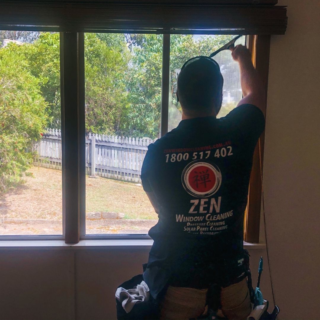 Professional window cleaner cleaning both interior and exterior sides of residential window
